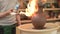 A potter burns an earthen jug with a gas burner at the final stage of the clay jug production
