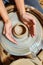 Potter clay pottery pot craft wheel hands. Potter\'s hands while working on the wheel, top view with dark background.