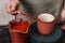 Potter or decorator painting ceramic clay cup in red color in pottery workshop or studio, crafting, artwork and handmade concept