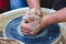 The potter forms a future product from a piece of clay on a potter`s wheel. Potter`s hands at work_