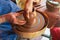 Potter makes on the pottery wheel clay pot. Hands of the master close-up during work. Ancient national craft
