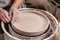 Potter making a big flat bowl of white clay on the potter`s wheel circle in studio, concept of creativity and art, horizontal
