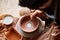 A potter paints a clay plate in a white in the workshop, top view, close-up, selective focus.