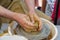 Potter in the process of working on a potters wheel. Close-up hands. Background with copy space