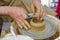 Potter in the process of working on a potters wheel. Close-up hands. Background with copy space