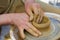 Potter in the process of working on a potters wheel. Close-up hands. Background with copy space