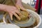 Potter in the process of working on a potters wheel. Close-up hands. Background with copy space