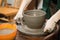 Potter's hands cutting pot with Cut-Off Wires close up. Woman works in pottery workshop. Clay bowl spinning on wheel