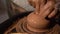 Potter`s hands shaping up the terracotta clay pot on wheal.