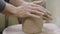 The potter's male hands knead and form soft, wet piece of white clay. Preparation of clay material for making handmade