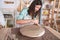 Potter woman shaping clay while working in a ceramic studio.
