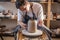 Potter working on a Potter`s wheel making a vase. Master processing the formed jug giving it the correct shape