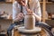 Potter working on a Potter`s wheel making a vase. Master processing the formed jug giving it the correct shape