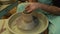 The potter works on a pottery wheel. Clay bowls made of soft colored clay