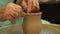 The potter works on a pottery wheel. Clay bowls made of soft colored clay