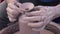 Potters hands covered in clay forming a pot on a wheel close up