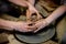 Pottery classes, student making clay pot on wheel. Close-up of dirty hands, sculpting clay crockery pottery training