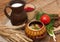 A pottery of cooked vegetables, a crock of milk, a wooden board with a tomato, cucumbers, bread and greens on a wooden surface