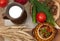 A pottery of cooked vegetables, a crock of milk, a wooden board with a tomato, cucumbers, bread and greens on a wooden surface