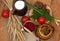 A pottery of cooked vegetables, a crock of milk, a wooden board with a tomato, cucumbers, bread and greens on a wooden surface