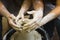 Pottery making. Smeared in clay hands of man and woman on potter`s wheel