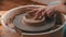 Pottery - master with finger is making the bottom for a clay bowl on the potter`s wheel