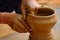 Pottery - skilled wet hands of potter shaping the clay on potter wheel