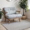 Pouf on blue carpet in bright living room interior with grey chair and settee against the wall with gallery