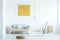 Pouf and table near grey sofa under yellow painting in modern li