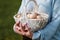 Poultry eggs lie in wicker basket in hands of woman.