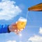 Pour beer into a glass against the sky.