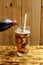 Pour cola from a bottle into a glass with ice