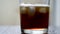 Pour cola into a glass with ice. Cold refreshing cola is poured into a glass with ice on a light background. Natural