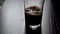 Pour cola into a glass with ice. Cold refreshing cola is poured into a glass with ice on a light background. Natural