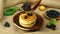 Pour fresh honey on a pile of pancake with blueberry in wooden bowl and tropical fruit