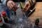 Pour oil onto a whetstone. The knifemaker is holding oil and a sharpener. The hands of the master