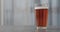 Pour orange fizzy drink into pint glass on concrete countertop with copy space