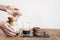 Pour over coffee brewing method Chemex, woman hands hold a glass bowl, still life with brownie cookies on wooden table.