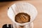 Pour over filter with ground coffee in the funnel in focus. Drip filter coffee brewing. Pour over alternative method of
