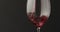 pour red wine into wineglass over black baground