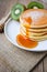 Pour syrup on stack of pancake on white plate and sackcloth with