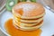 Pour syrup on stack of pancake on white plate and sackcloth with