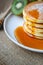 Pour syrup on stack of pancake on white plate and sackcloth with