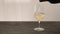 Pour white whine in wine glass on oak table