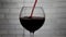 Pour wine into a glass, red wine into a glass against a white brick wall background,close-up of wine.