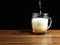 Pouring beer into big glass jar on a brown wooden table. Alcohol consumption. Dark background