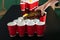 Pouring of beer from glass bottle into plastic cups on table. Beer pong game