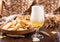 Pouring beer into the glass. Wheat spikelets with one mugs of beer on wooden background