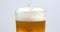 Pouring beer on a pint glass with white background