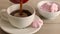 Pouring black coffee in cup. Cup of black coffee with marshmallow desserts on a wooden table